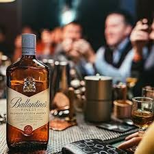 Ballantine's whiskey bottle on a table with people in the background