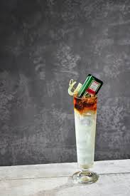 Cocktail in a glass with a light bulb and lighter on a dark background