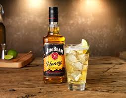 Jim Beam Honey bottle with a glass of iced cocktail on a wooden surface