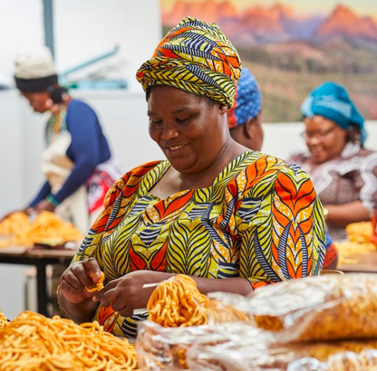 Woman in colorful traditional attire working with food at a market stall.