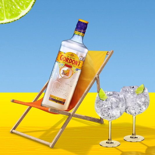 Gordon's gin bottle with two glasses on a bright yellow surface and blue background