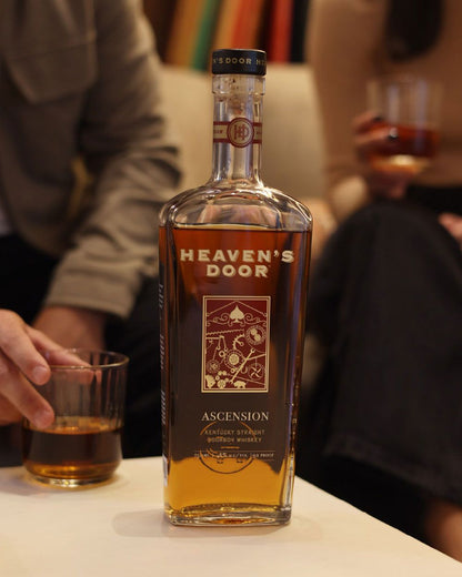 Bottle of Heaven's Door whiskey on a table with people in the background