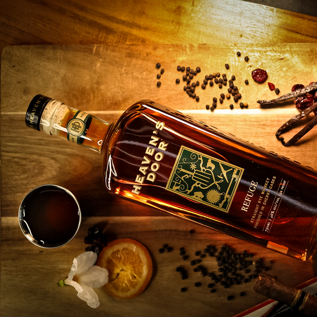 Bottle of Heaven's Door whiskey on a wooden surface with spices and a glass of dark liquid.