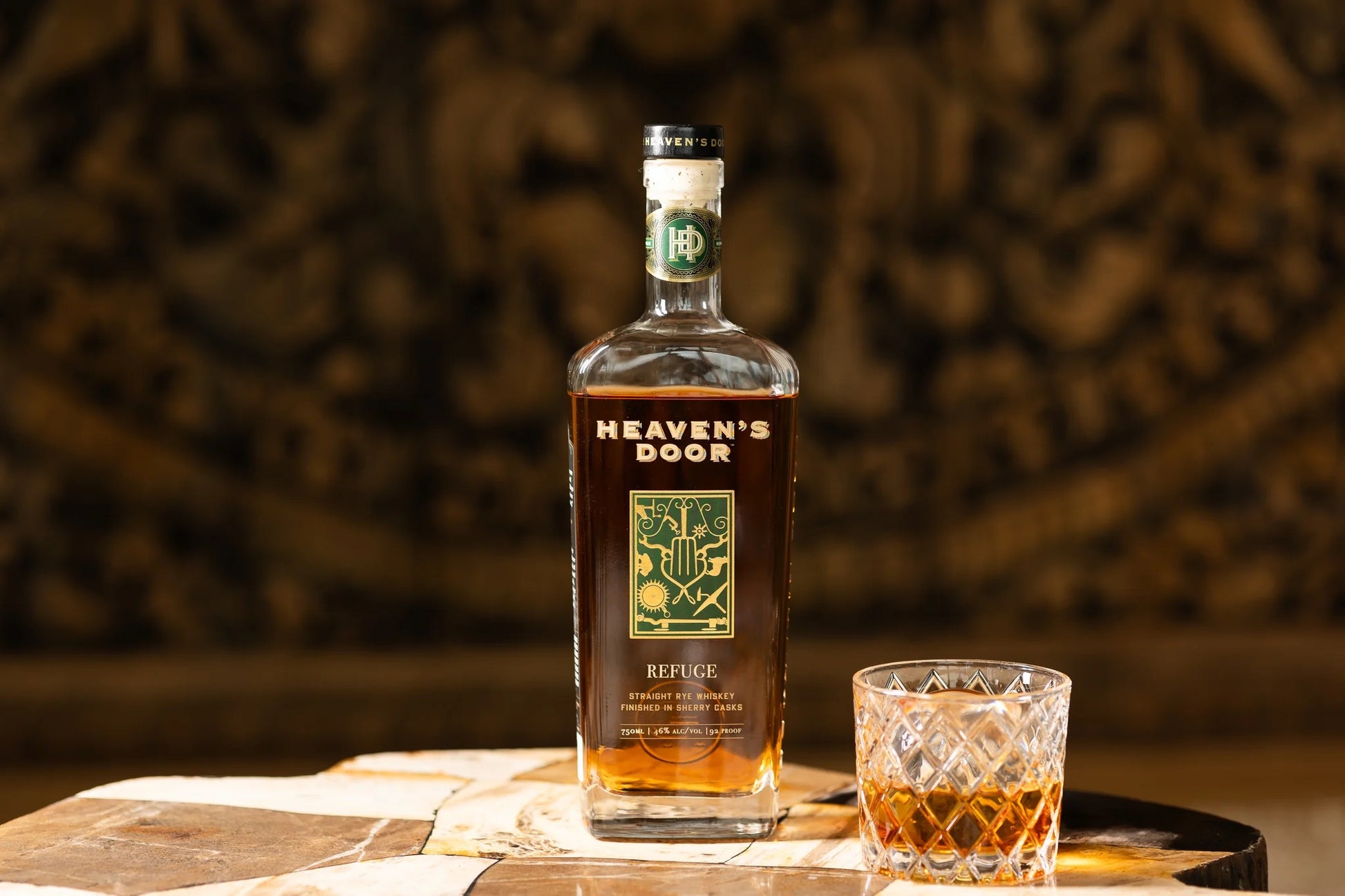 Bottle of Heaven's Door whiskey with a glass on a wooden surface