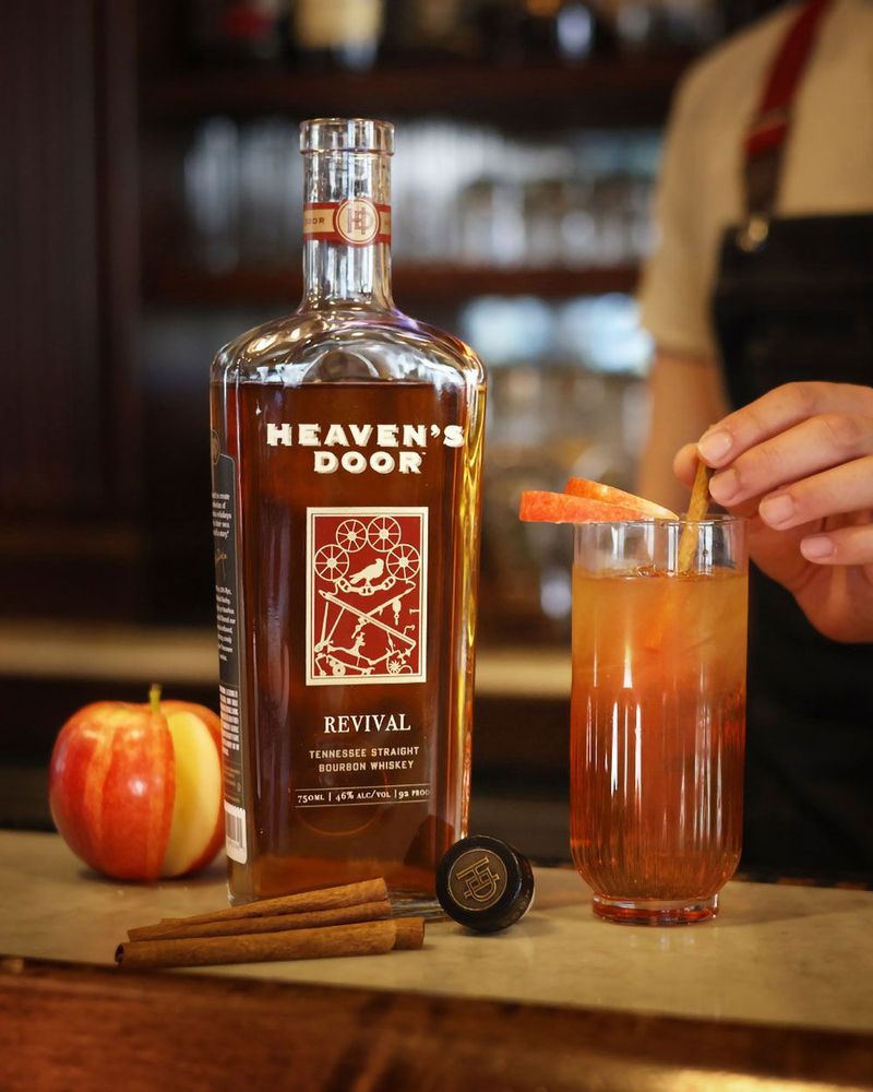 Heaven's Door whiskey bottle with a cocktail and garnish on a bar counter