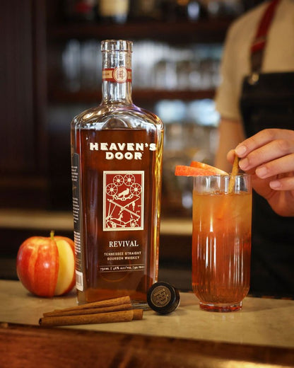Heaven's Door whiskey bottle with a cocktail and garnish on a bar counter