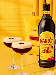 Bottle of Kahláua coffee liqueur with two cocktails on a yellow background