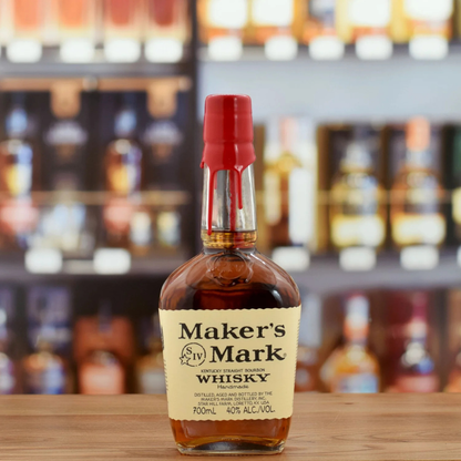 Bottle of Maker's Mark Whisky on a wooden surface with blurred bottles in the background