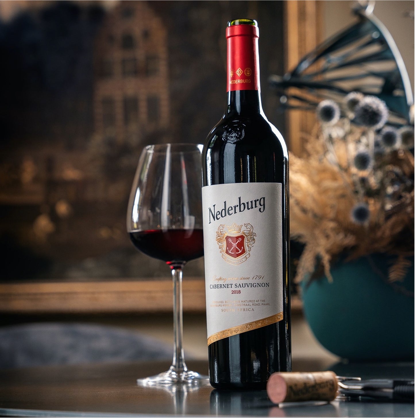 Nederburg Cabernet Sauvignon wine bottle with a glass of wine on a table.