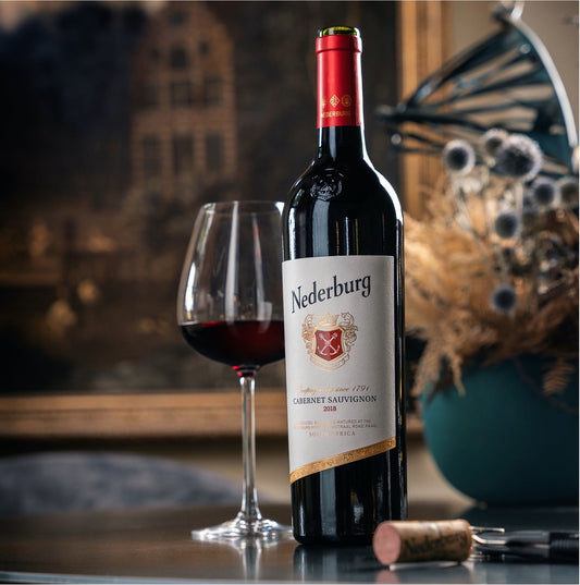 Nederburg Cabernet Sauvignon wine bottle with a glass of wine on a table.