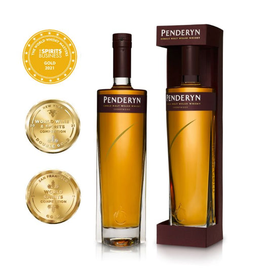 A bottle of Penderyn Welsh Single Malt Whisky with a Sherrywood finish, accompanied by a gold and a bronze award coin, all presented in a branded cardboard packaging.