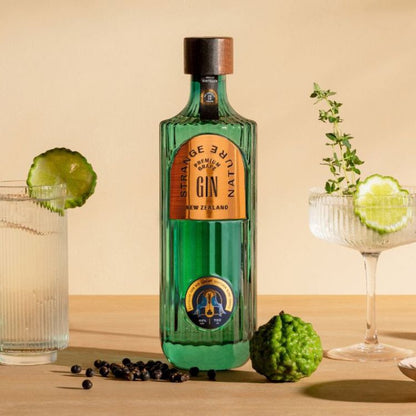 Green bottle of Heritage Pure Gin with garnishes on a wooden surface