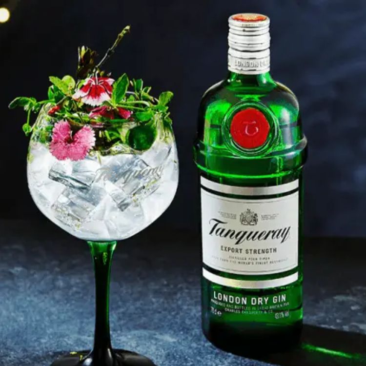 Tanqueray gin bottle with a cocktail garnished with flowers on a dark background